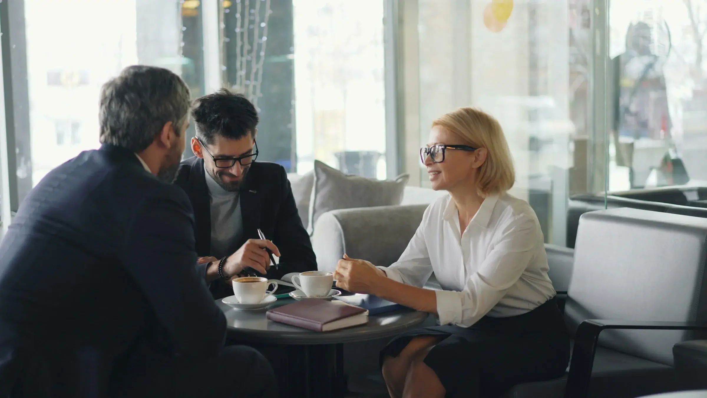 Three professionals in conversation around a meeting table