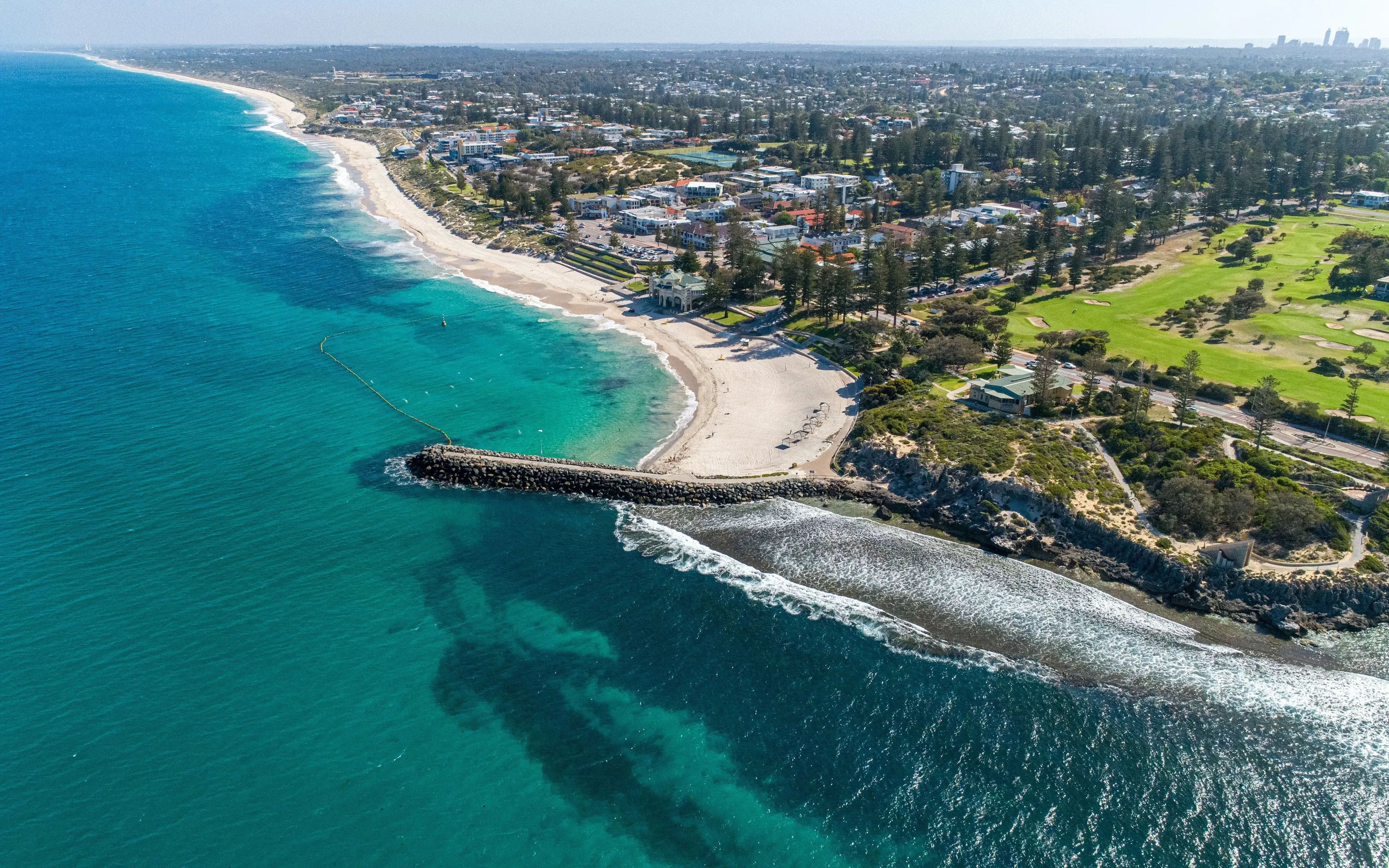 Aerial view of a Western Australian beach, breakwater and suburbs