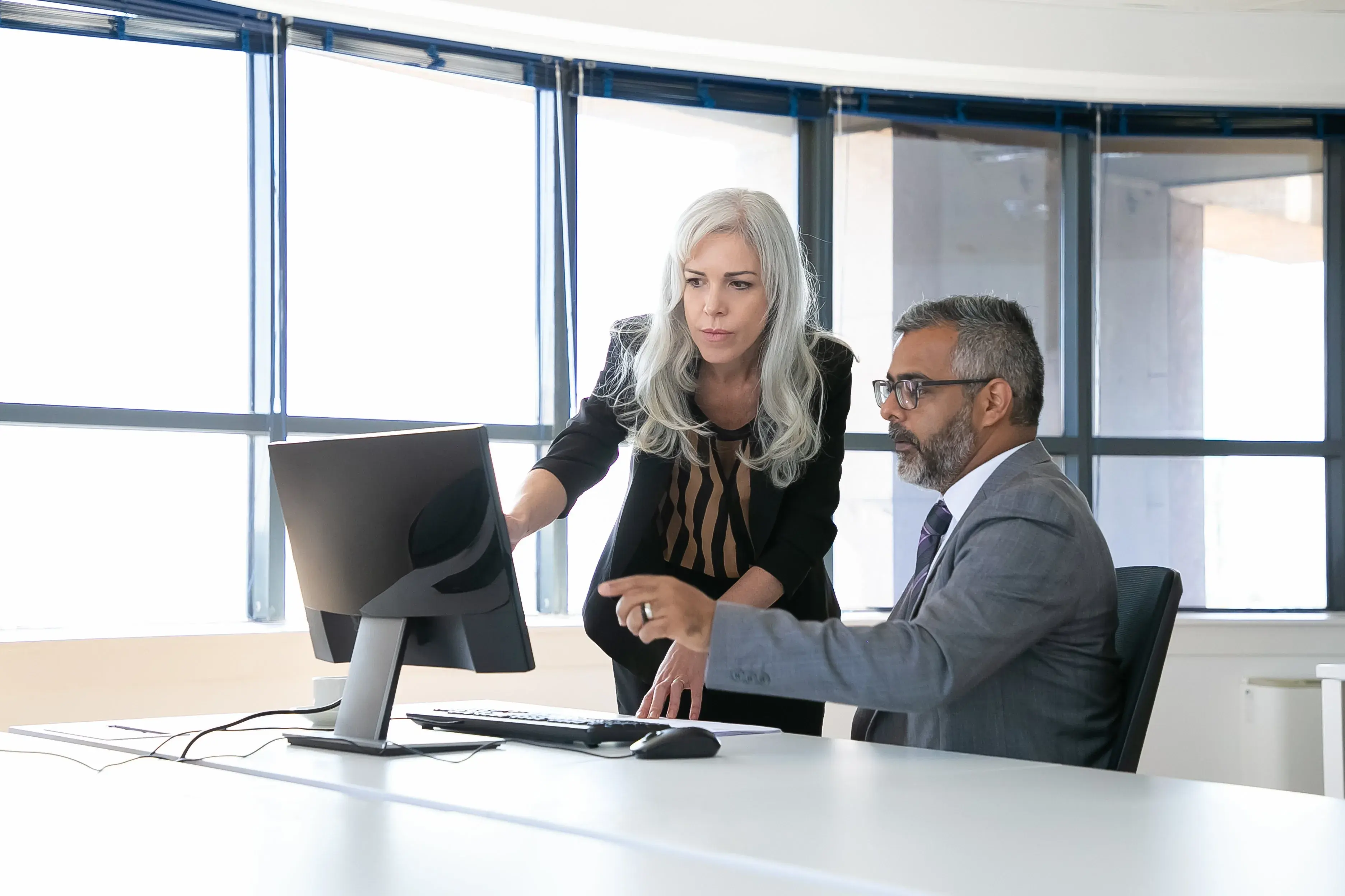 Colleagues reviewing information together on a shared screen in a bright meeting room