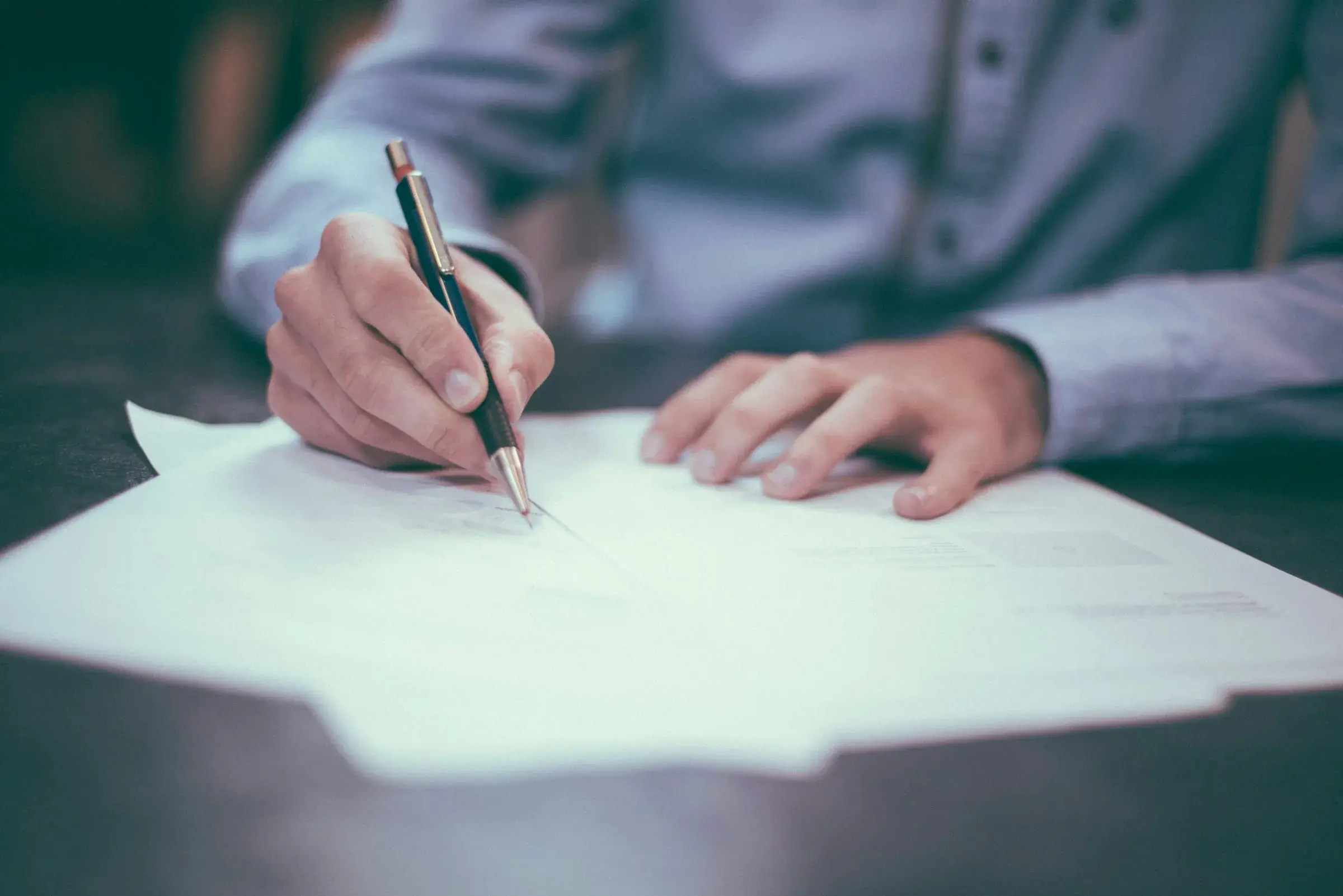 A person writing on a printed document