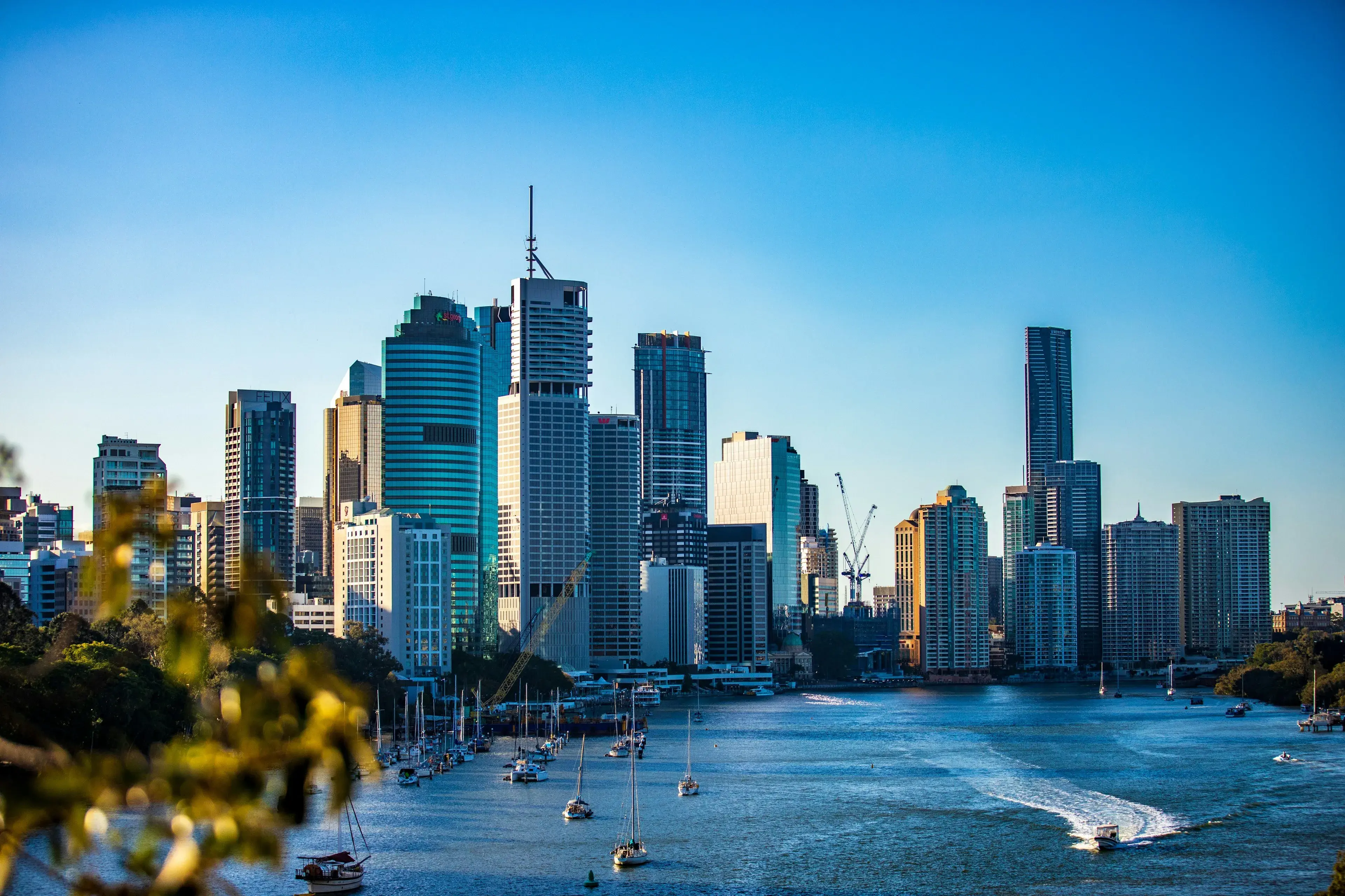 Brisbane city skyline and the Brisbane River under a clear blue sky