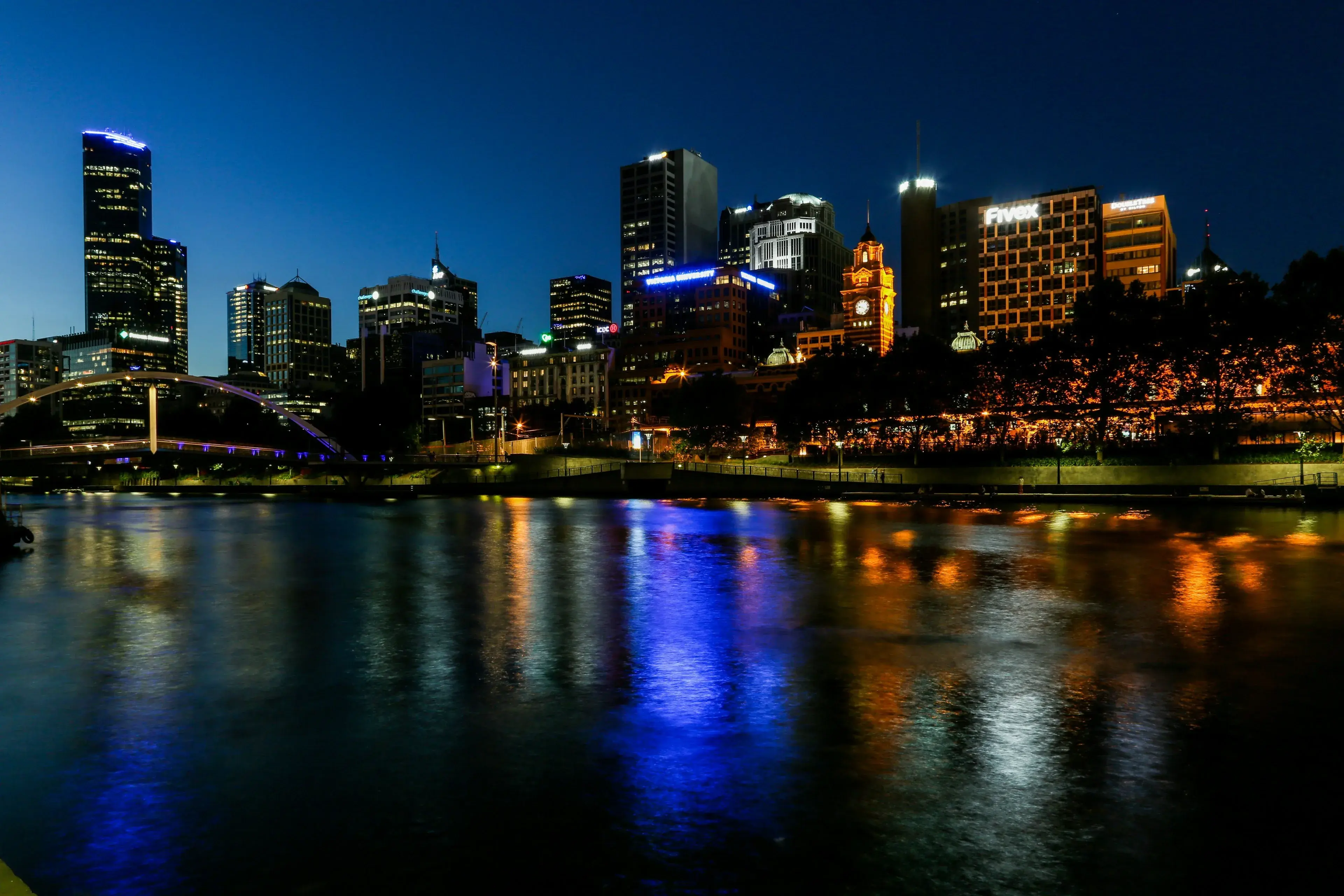 City towers lit up at night and reflected in the river