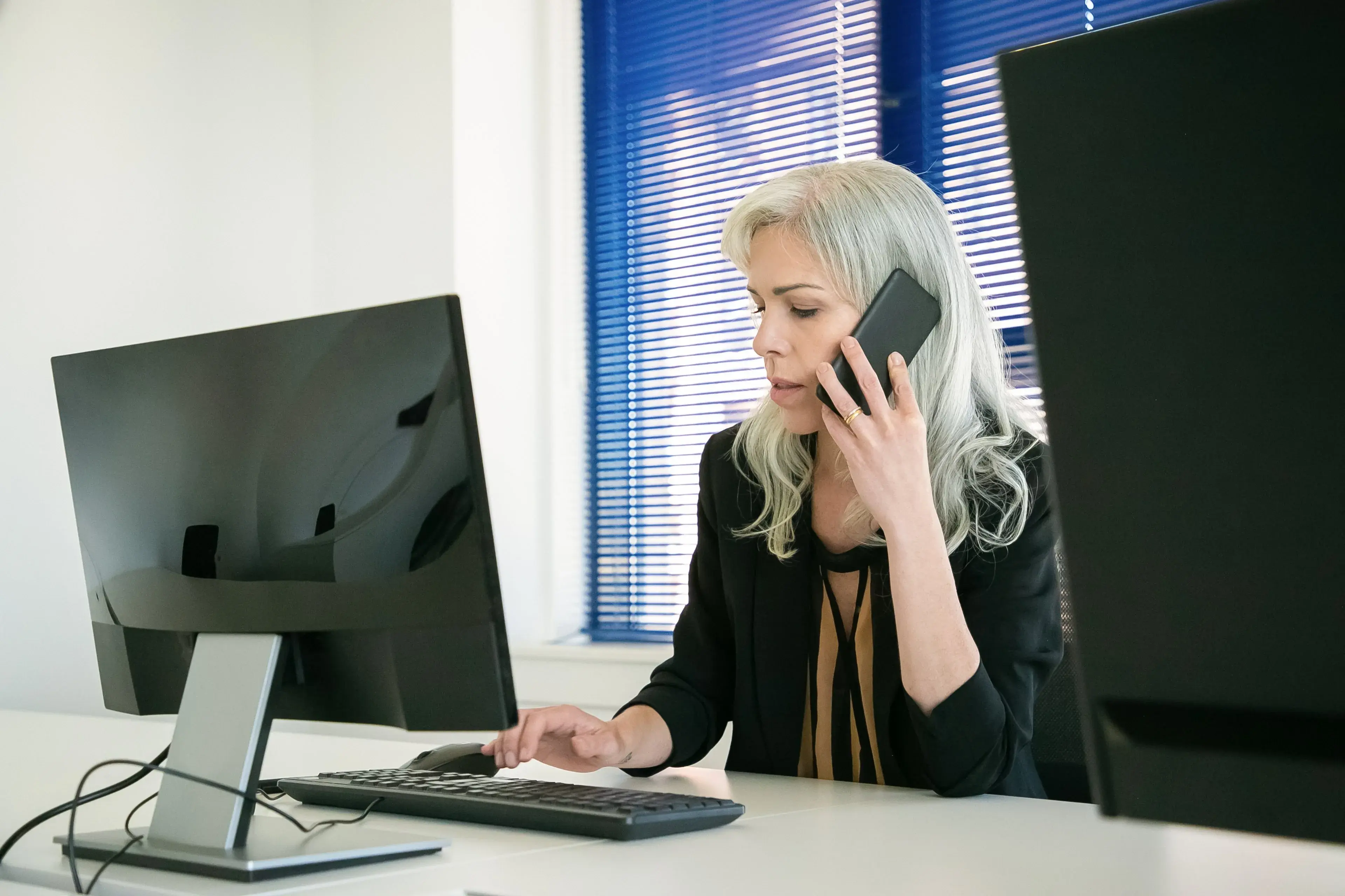 A professional on a phone call while typing at her desk