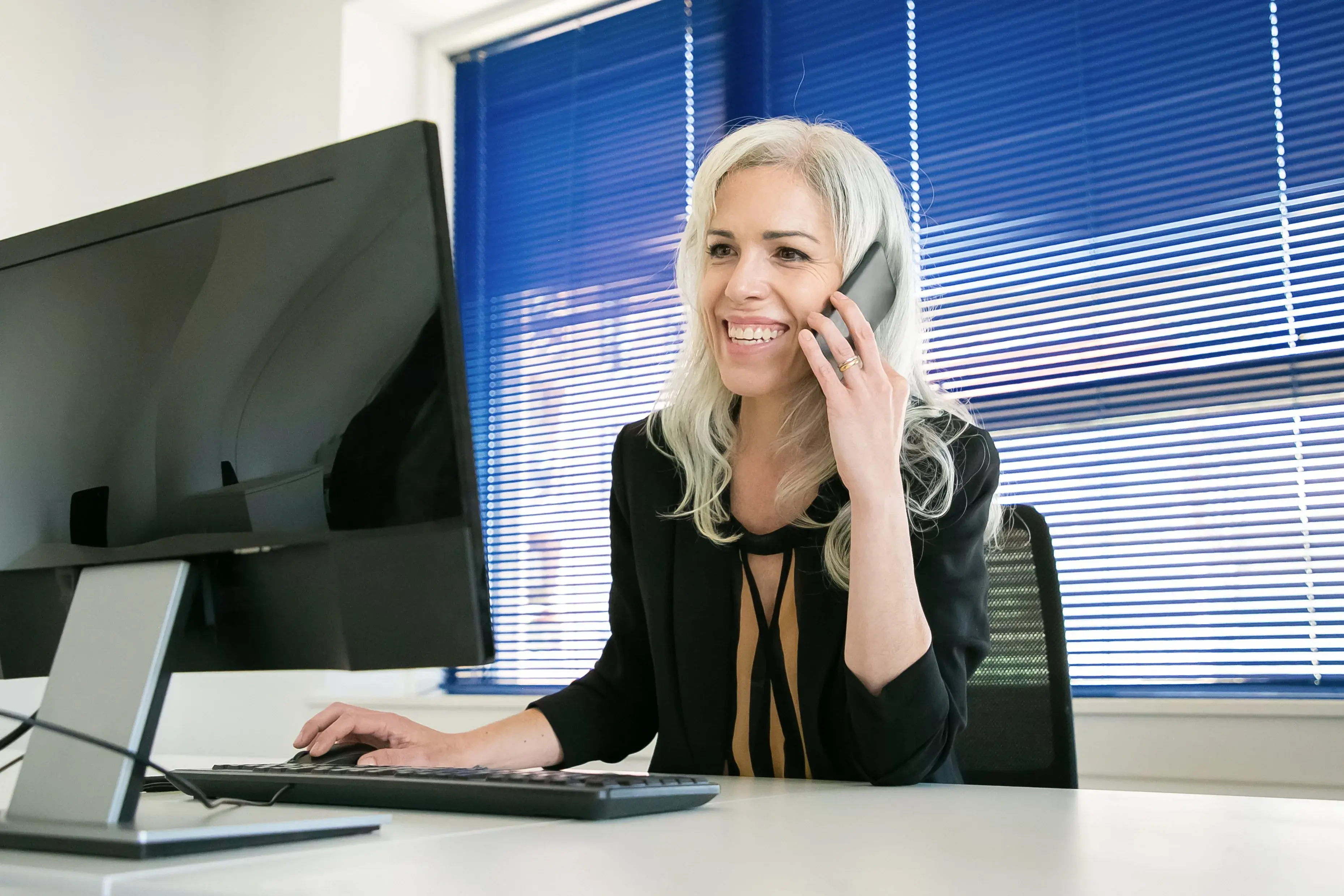 A professional smiling during a phone call at her computer