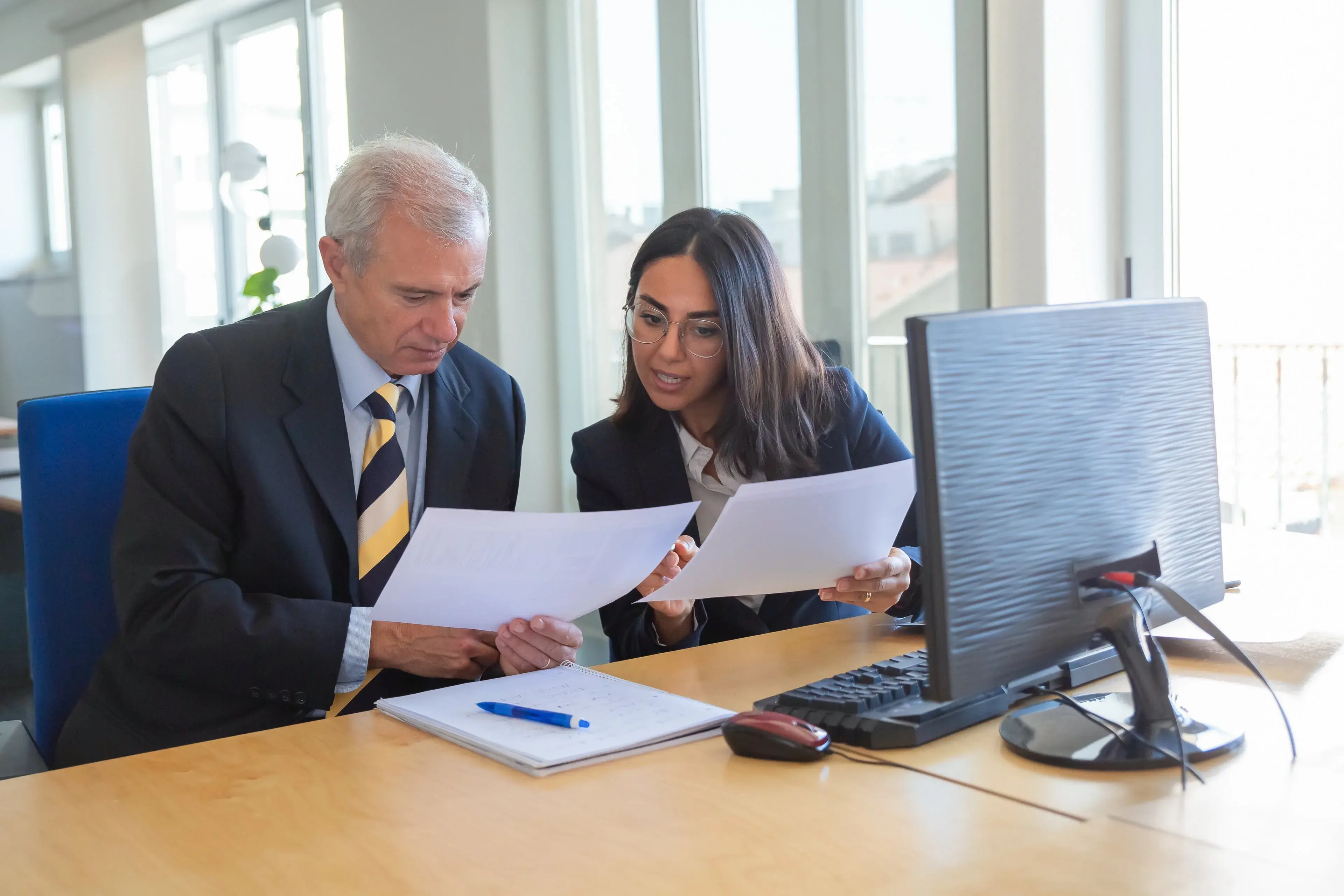 A professional explaining a document to a client at a desk