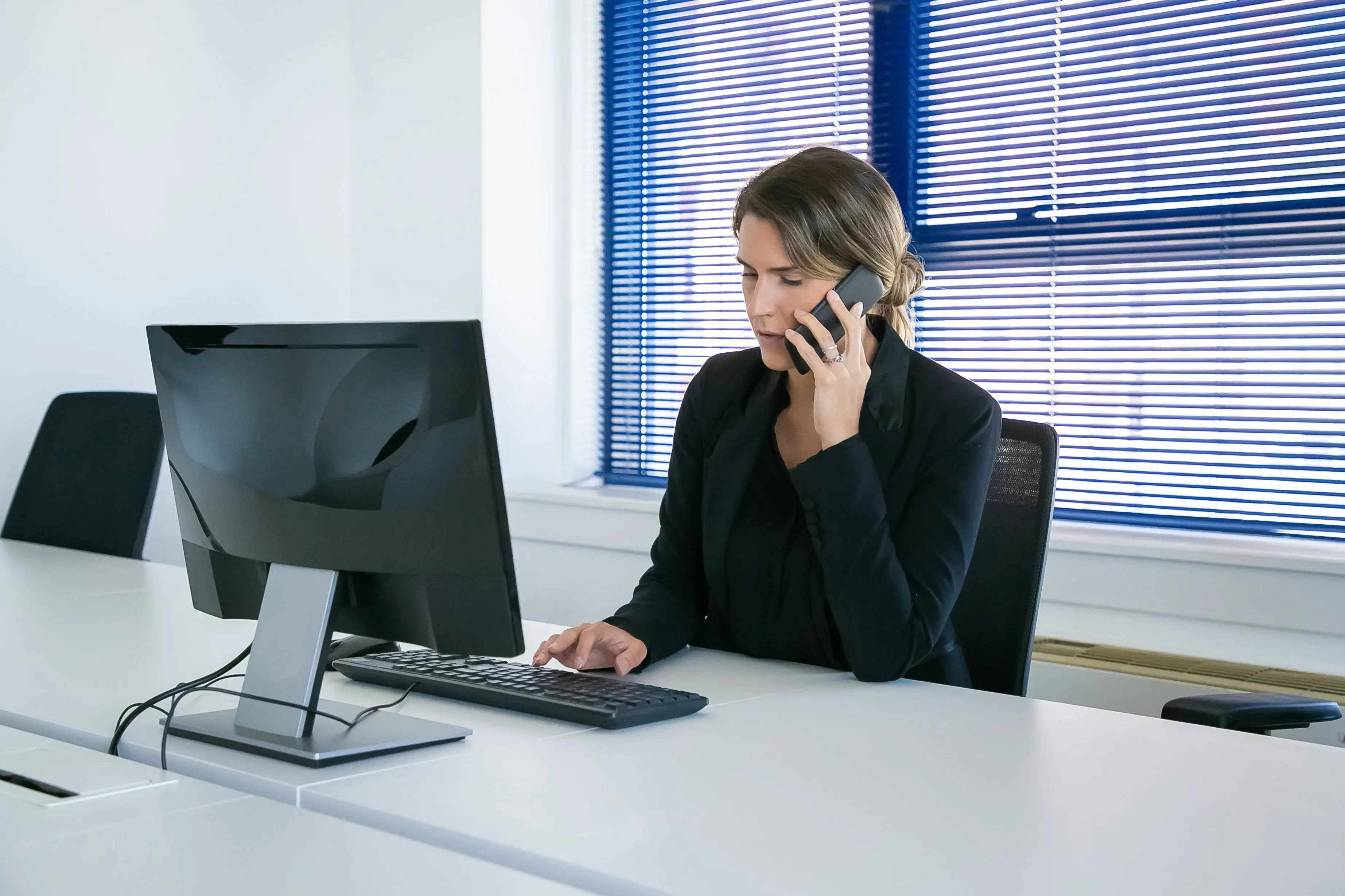 A professional taking a call while working at her computer