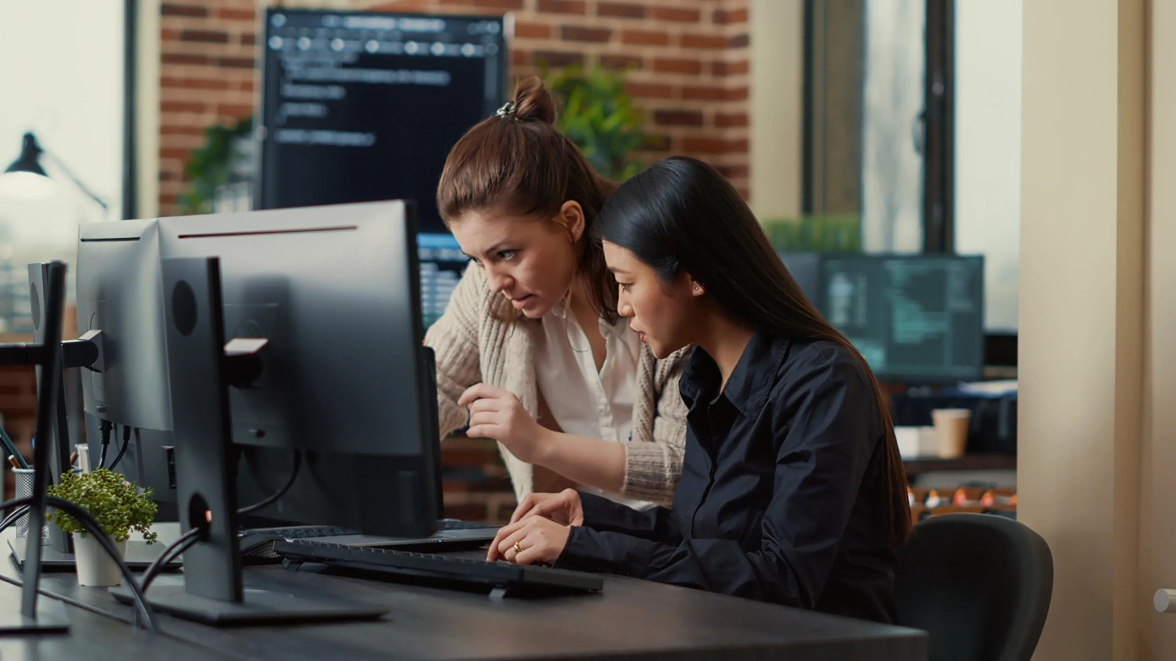 Colleagues working through a setup together at a desk with two screens
