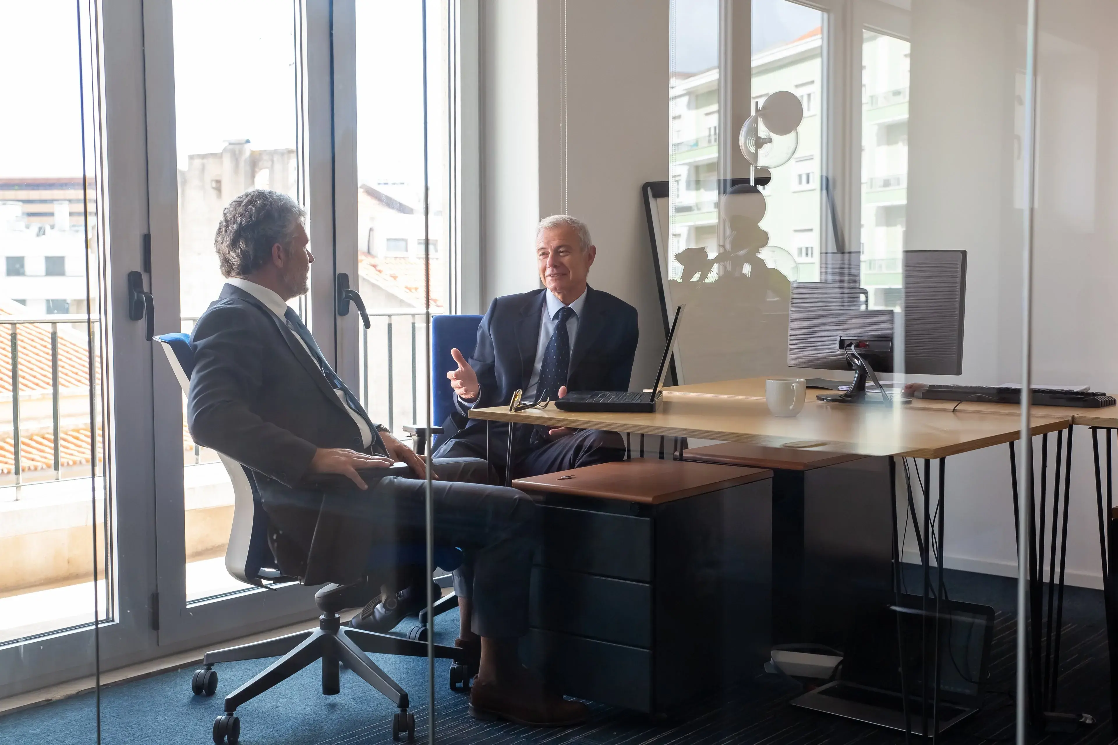 Two professionals in conversation in a glass-walled office