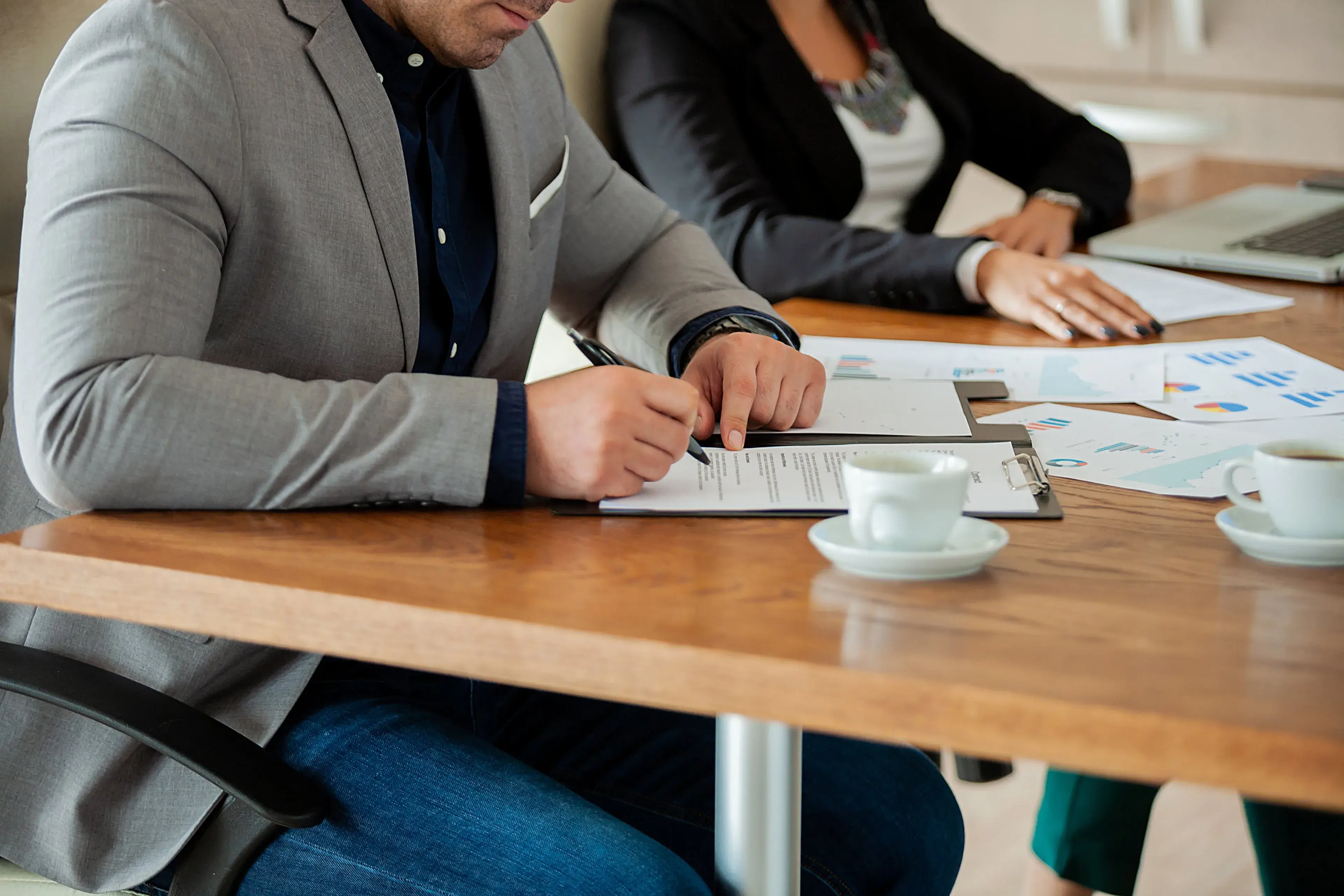 A person signing paperwork at a meeting table